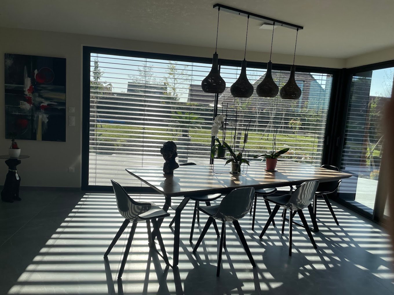 Salle à manger lumineuse rénovée par DL Peintre Décorateur, stores vénitiens et suspensions noires