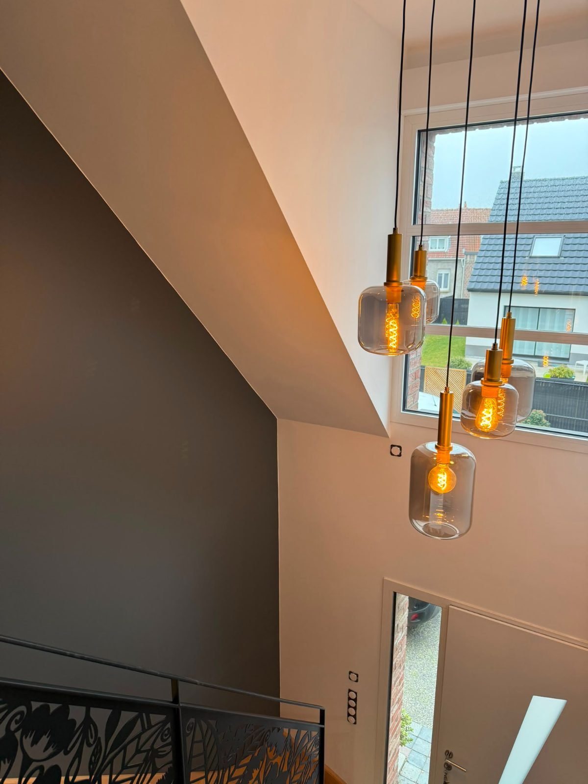 Cage d'escalier — mur sombre et suspensions en verre fumé