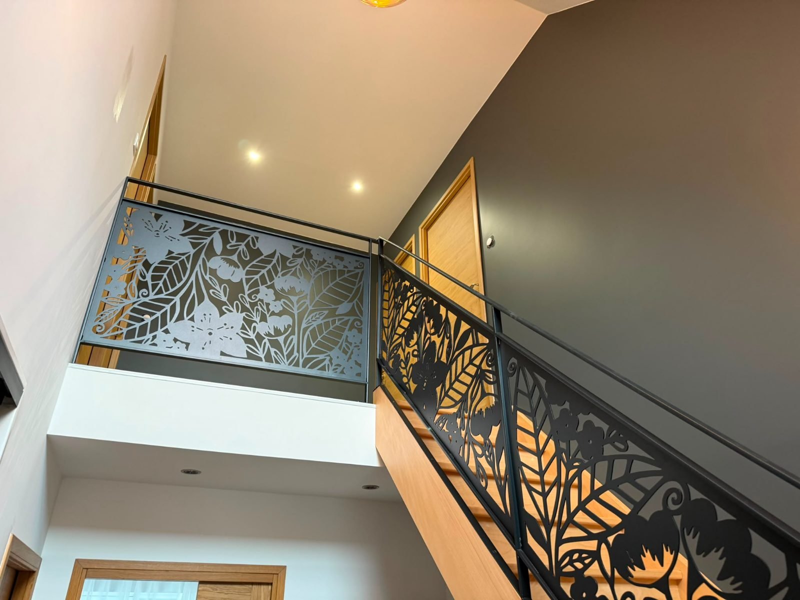 Palier — garde-corps en métal découpé à motif floral, mur taupe