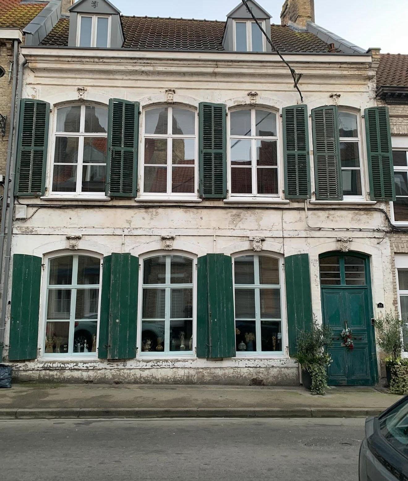 Façade de maison flamande — enduit écaillé et volets verts, avant travaux