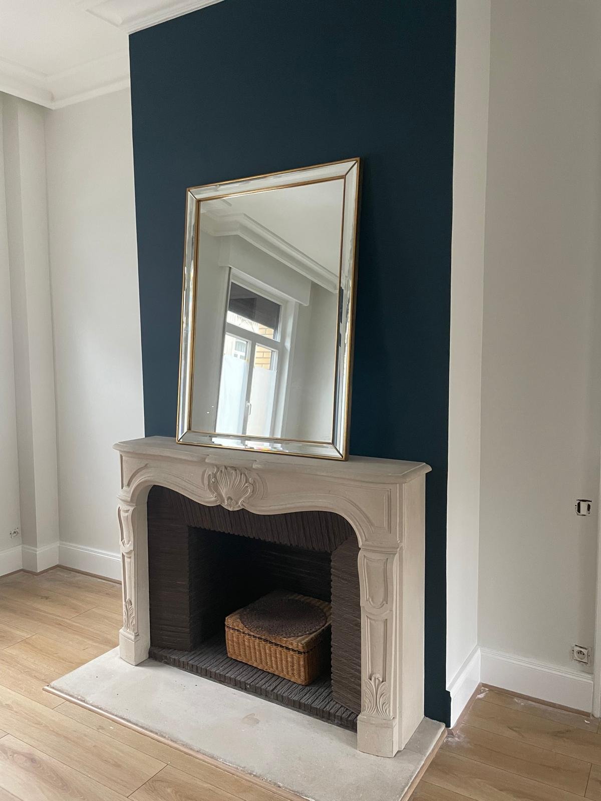 Détail — cheminée en pierre et miroir doré sur mur bleu canard